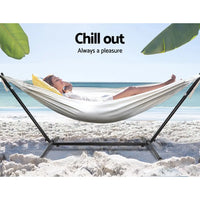 Woman relaxing in a cream hammock with steel stand on the beach