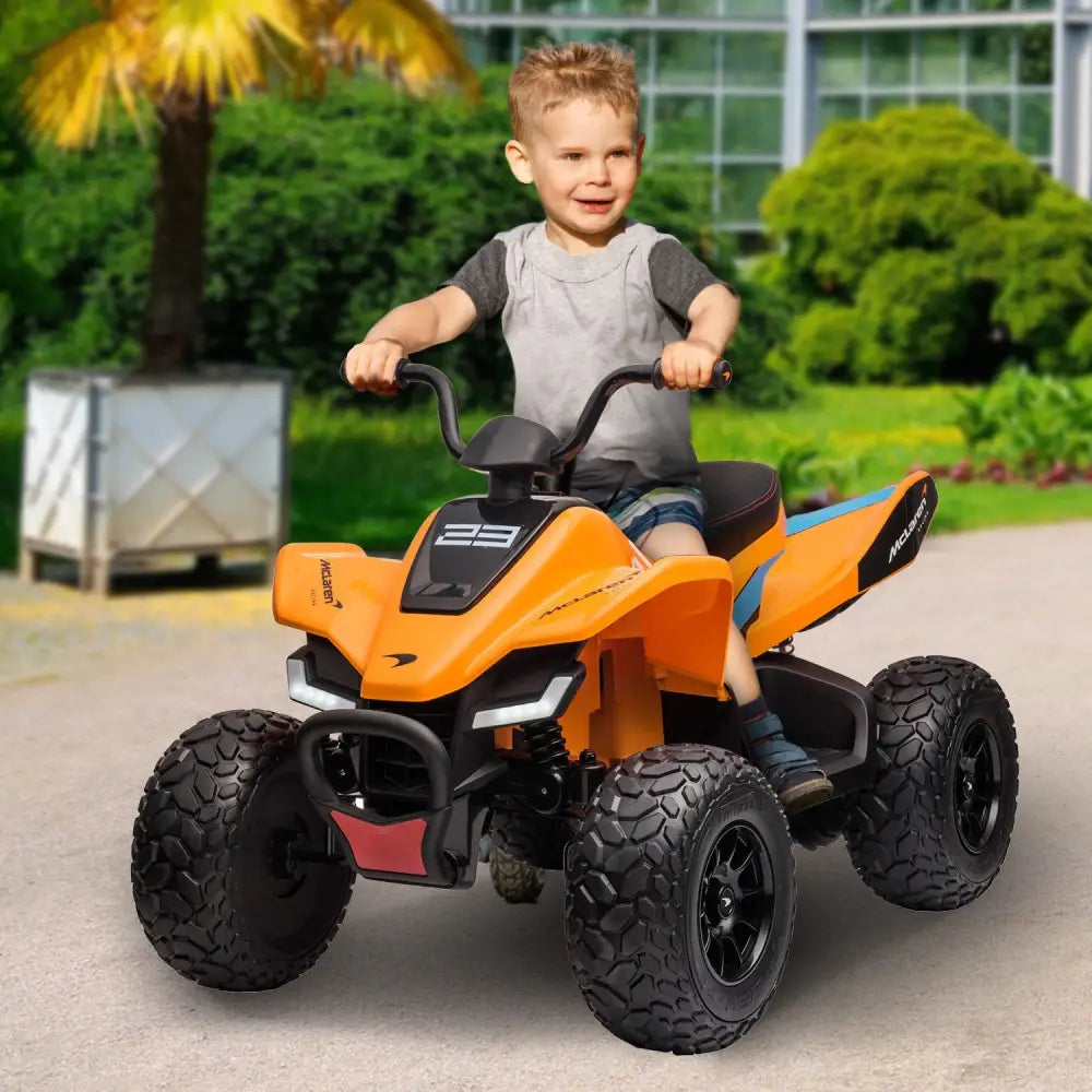 Young boy riding orange toy atv with working led lights - mclaren kids ride on electric quad bike