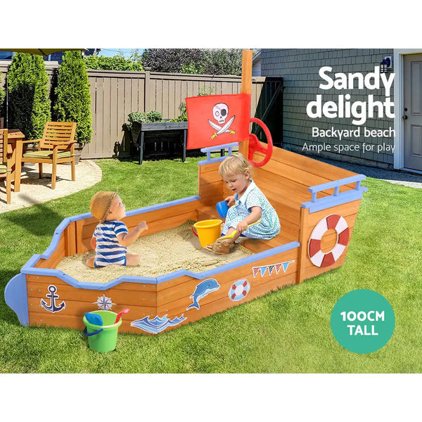 Child playing in boat-shaped sand pit sandbox with pirate ship toy