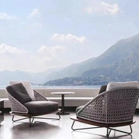 Modern outdoor furniture set with a scenic view of mountains and water.