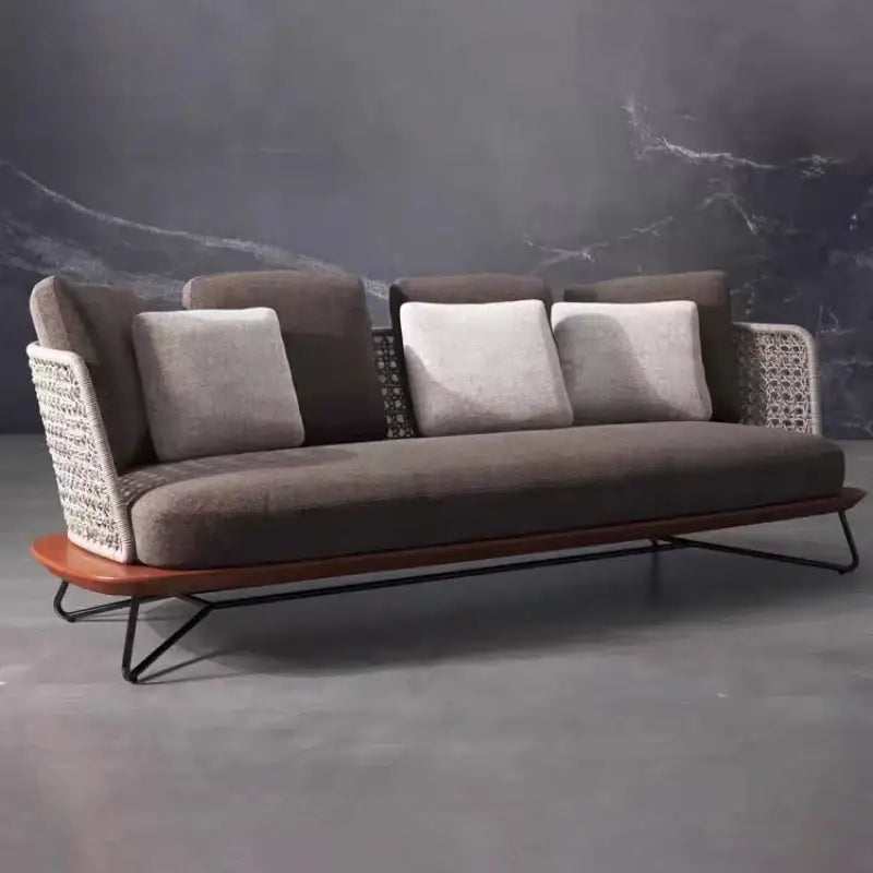 Modern sofa with wicker backrest and wooden base against a dark marble wall.