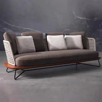 Modern sofa with wicker backrest and wooden base against a dark marble wall.