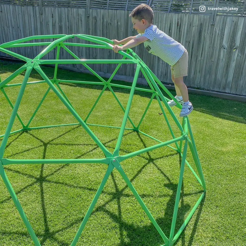 Boy playing with a green plastic ball on rust resistant powder coated steel dome climber