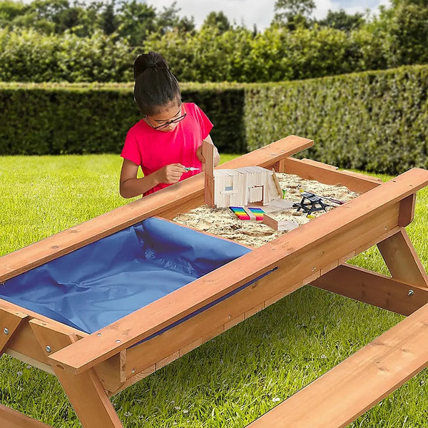 Young girl playing with sand & water wooden picnic table