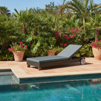 Chaise lounge by a pool with potted plants and flowers